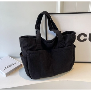 Détail d'un sac cabas en velours côtelé noir montrant le tissu et la poche avant
