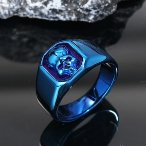 Close-up of deep blue skull ring with high-gloss finish and textured relief on dark background