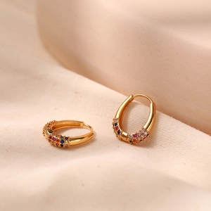 Macro view of gold-plated oval hoop earring with multi-color cubic zirconia settings