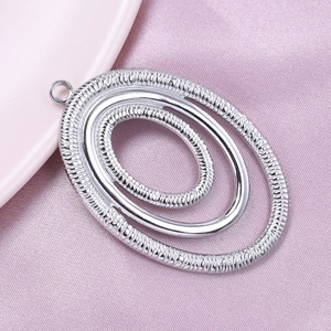 Macro shot of silver-toned concentric oval pendant with rope texture and polished layers