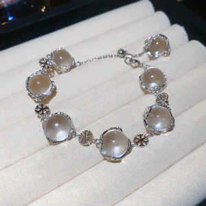 Close-up of snowflake charm beaded bracelet on a cream-white velvet jewelry box