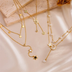 Three gold stainless steel layered necklaces with stars and pearls on silk fabric