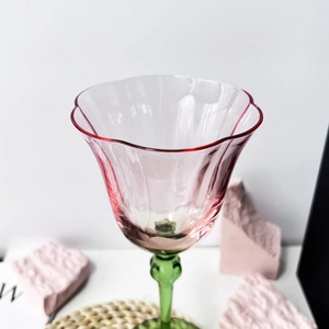 Detail of pink fluted glass goblet with green stem on a textured stone base