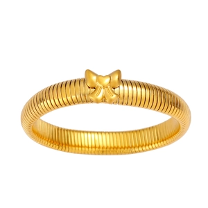 Détail du bracelet doré avec nœud papillon, motif cœur et structure en spirale