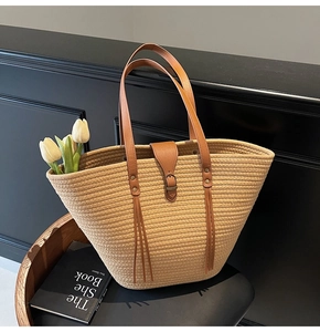 Detail of khaki woven straw tote bag with brown leather straps and white tulips