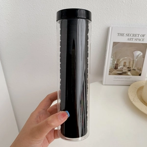 Close-up of black high-elastic hair bands in a transparent cylindrical storage container