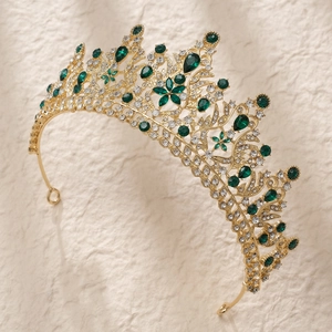 Detail of luxury gold alloy tiara with green teardrop gems and sparkling rhinestones