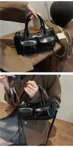 Macro view of black glossy saddle bag featuring double front pockets and silver zippers