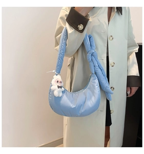Détail latéral du sac croissant bleu clair avec pendentif lapin et anse à nœud
