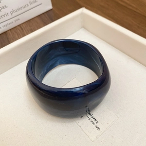 Close-up of deep blue marble pattern acrylic bangle with a chunky minimalist design