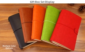 Stack of vintage leather travel journals in five colors with elastic straps on wood