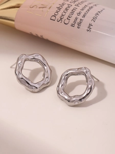 Macro shot of silver textured irregular wave earrings on a minimalist background