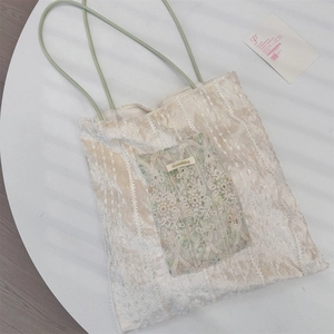 Détail de la texture en dentelle florale et de la poignée en corde verte du sac beige