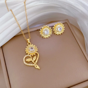 Detailed close-up of golden sunflower jewelry set with white zircons on silk background