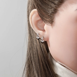 Silver anchor stud earring with zircon stones shown on a model's ear cartilage