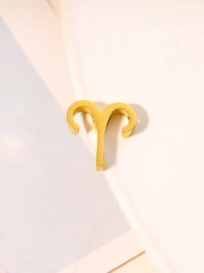 Macro shot of polished gold Aries zodiac sign pendant charm in stainless steel