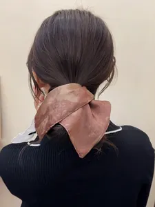 Detail of vintage marble-patterned brown silk scrunchie on a low ponytail hairstyle
