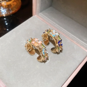 Macro detail of gold-plated floral ring with colorful enamel petals and crystal accents