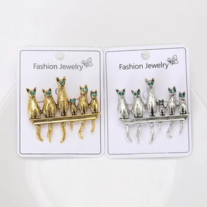 Detailed close-up of retro cat brooches set in gold and silver with green rhinestone eyes