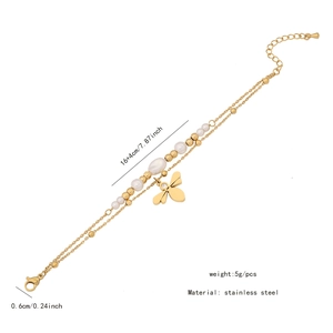 Détail d'un bracelet double couche en acier doré avec perles blanches et pendentif abeille