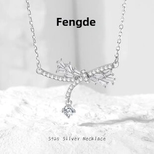 Macro shot of S925 silver bow pendant necklace with cubic zirconia on white stone