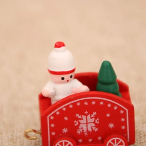 Macro shot of red wooden Christmas train detail with mini baby doll and snowy tree