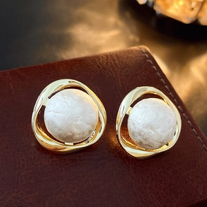 Detailed view of gold geometric stud earrings with textured baroque faux pearl inlays