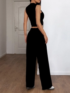 Vista posteriore di un completo nero due pezzi da donna con crop top e pantaloni larghi