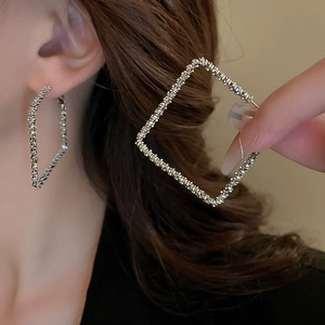 Macro shot of silver geometric square earrings with textured surface and metallic shine