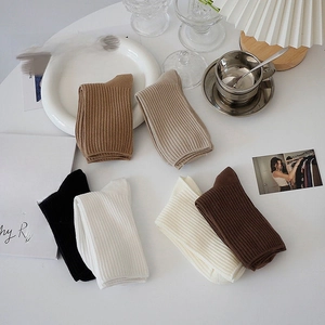 Detailed view of thick ribbed cotton crew socks in neutral earthy tones on a minimalist desk