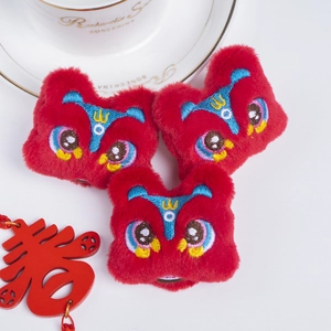 Macro shot of three red plush Chinese lion brooches with embroidery on white background