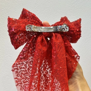 Détail du nœud rouge à paillettes montrant le fermoir à ressort en métal argenté robuste