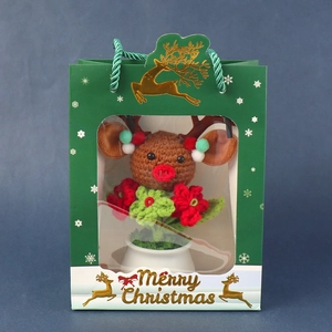 Close-up of crochet reindeer Christmas decor in a mini pot with festive gift bag