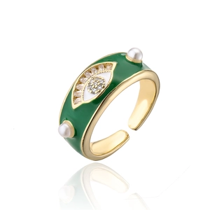 Macro detail of gold evil eye ring with green enamel, white rhinestones and pearls
