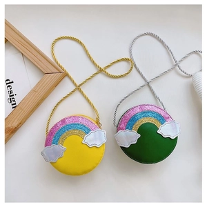 Detail view of round cartoon rainbow crossbody bags in vibrant yellow and green PU leather