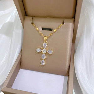 Detailed shot of a gold cross necklace with teardrop zircons in a luxury jewelry box