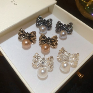 Détail de trois paires de boucles d'oreilles nœud et perle en gris, or et argent