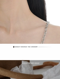 Close-up of a minimalist silver chain necklace featuring wrinkled texture and metal links