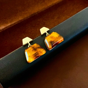 Detailed close-up of retro trapezoid resin earrings with gold plating and amber texture