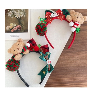 Flat lay of red and green plush Christmas bear headbands with festive bows and pom-poms