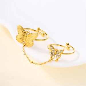 Macro detail of gold bow and flower rings with pearls and delicate chain connection