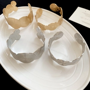 Detailed top view of minimalist gold and silver spiral textured open bangles on a tray