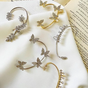 Elegante Schmetterling-Ohrklemmen mit Strassbesatz und Goldbeschichtung auf Vintage-Hintergrund