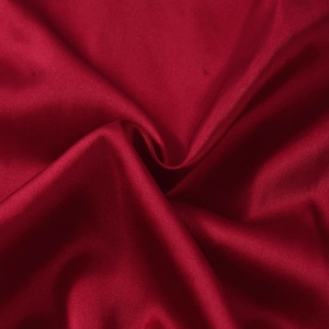 Détail macro de la texture satinée rouge avec des plis soyeux élégants et une finition brillante