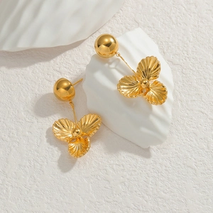 Elegant gold flower tassel drop earrings with textured surface on a white stone background