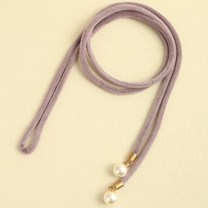 Detail of lavender velvet cord accessory featuring white pearl charms and gold metal tips