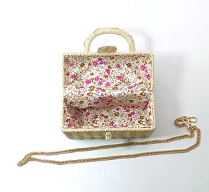 Detail view of woven straw box bag with floral fabric lining and gold chain strap