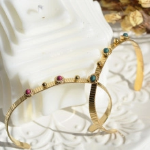 Detailed shot of golden headband with red and green beads on an elegant white tray