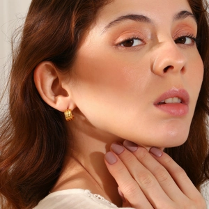 Three-layer 18K gold plated stainless steel hoops worn by a model in a close-up shot