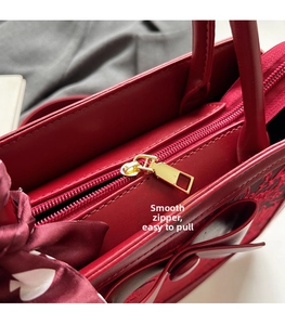 Close-up of smooth golden zipper and red jacquard texture on bridal handbag